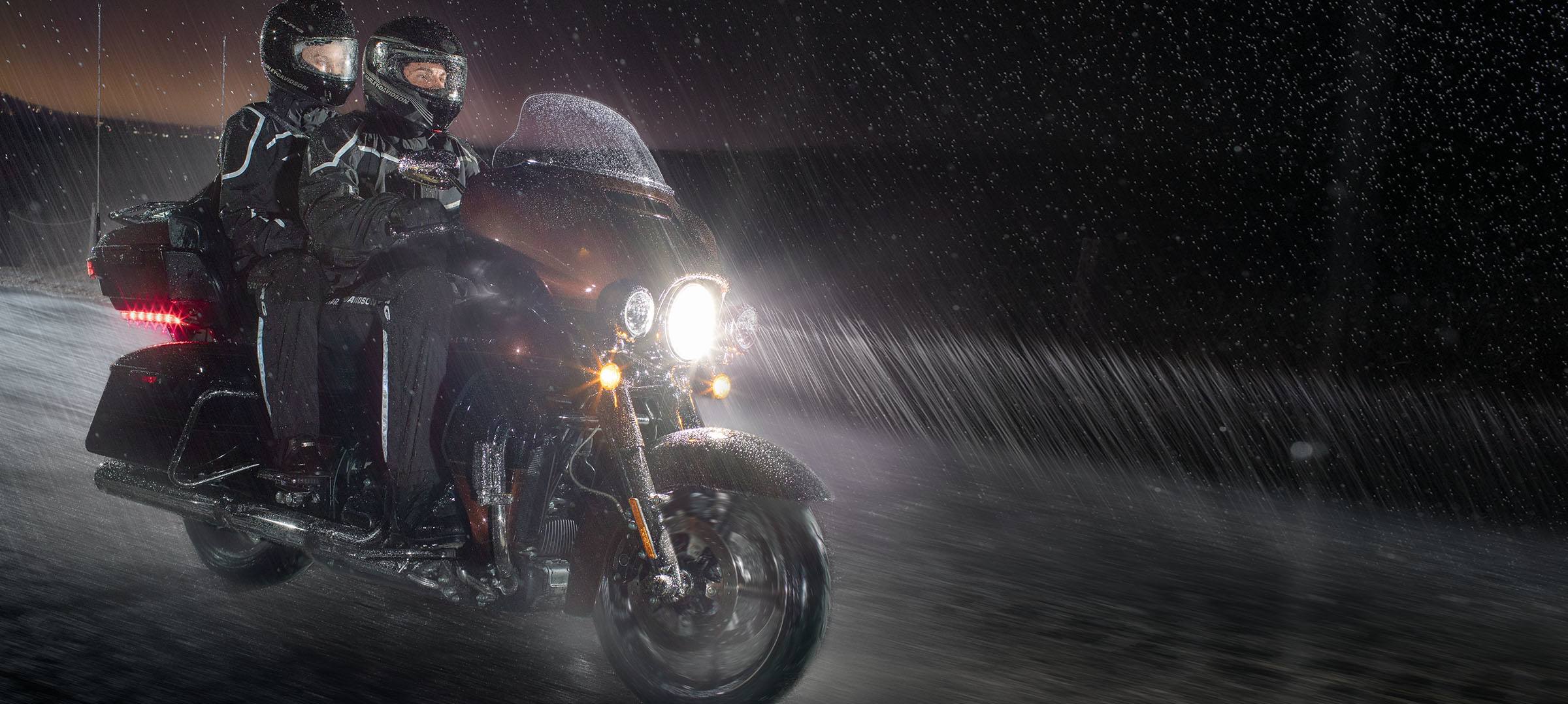 two people riding a harley davidson in the rain